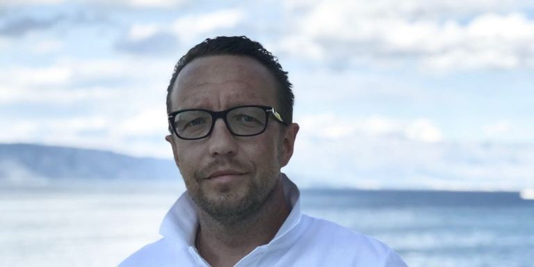 Andreas steht am Meer mit einem Glas Wein