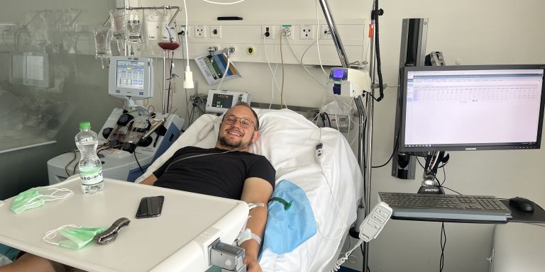 Un jeune homme souriant sur son lit d'hôpital pendant le don de cellules souches du sang