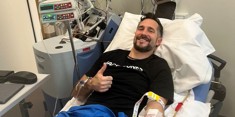 Christian Rebholz liegt im Spitalbett während der Spende, lächelt und reckt einen Daumen in die Höhe