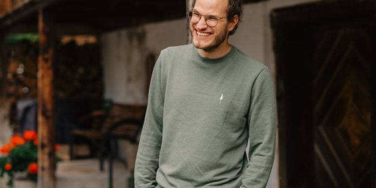 Thomas Hadorn se tient devant une ferme et sourit.