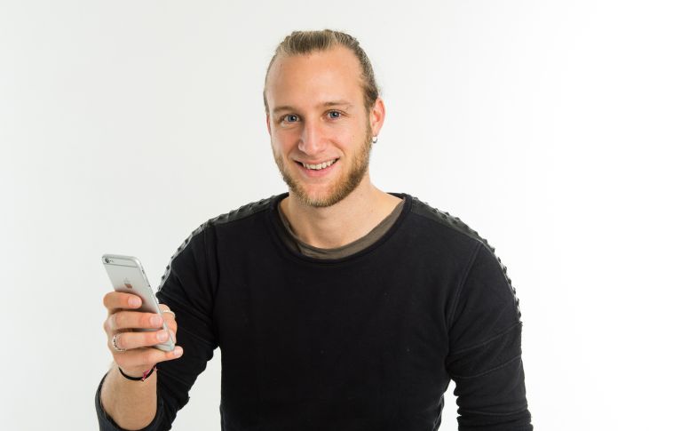 Junger Mann lächelt und hält sein Handy in der Hand