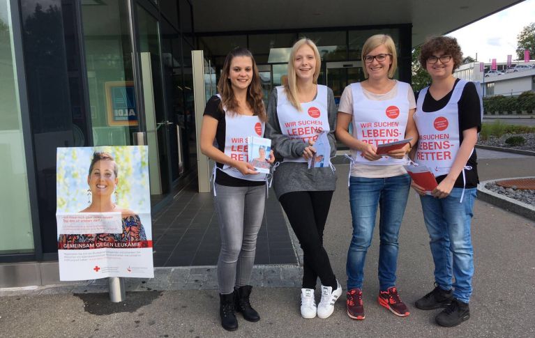 Vier junge Frauen stehen draußen und werben für eine Blutspendeaktion