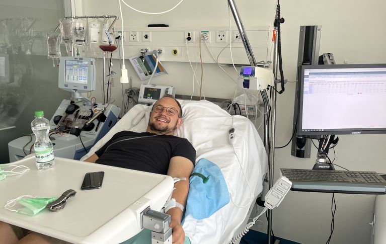 Un jeune homme souriant sur son lit d'hôpital pendant le don de cellules souches du sang