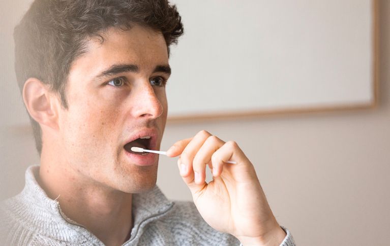 Un jeune homme prélève un échantillon de tissu dans sa bouche à l'aide d'un bâtonnet de test pour le don de cellules souches du sang