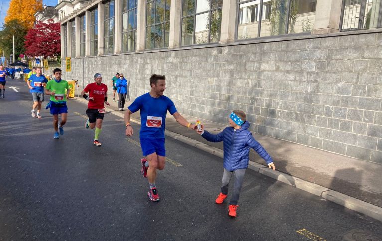 Raphael beim Marathon, sein Sohn gibt ihm eine Wasserflasche