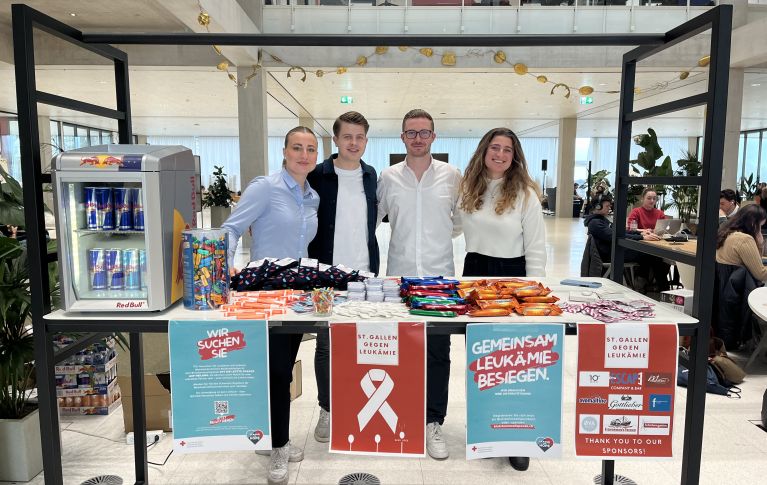 Vier Studierende stehen hinter ihrem Stand mit Give Aways und Informationsmaterial zur Blutstammzellspende