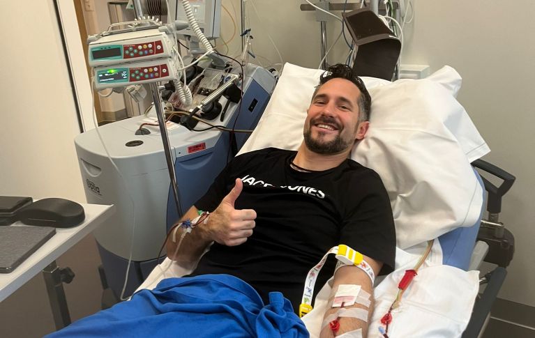 Christian Rebholz liegt im Spitalbett während der Spende, lächelt und reckt einen Daumen in die Höhe