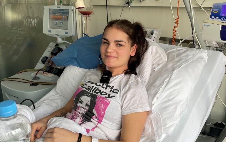 Nora liegt während ihrer Blutstammzellspende in einem Krankenhausbett und blickt in die Kamera.