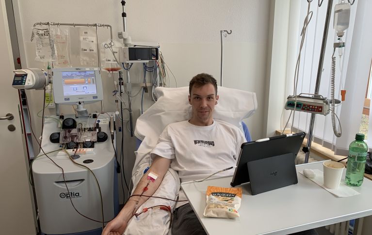 Severin Schmugge während der Blutstammzellspende im Spitalbett, vor sich ein iPad und Nüsse