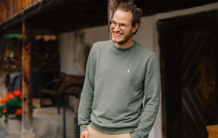 Thomas Hadorn se tient devant une ferme et sourit.