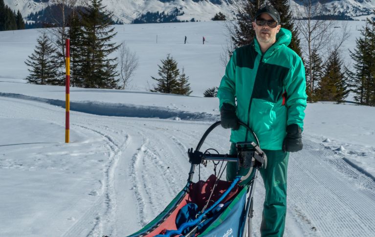 Jürg Zürrer steht im Winter auf einem Hundeschlitten.