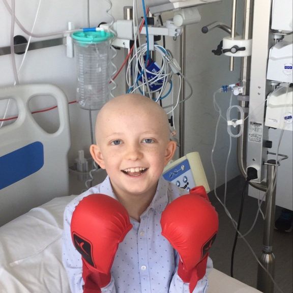 Der 9-jährige Daniel sitzt in einem Spitalbett und hat rote Boxhandschuhe an.
