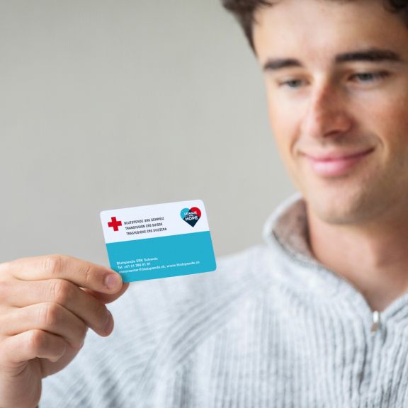 Un giovane uomo guarda la sua tessera di donatore per la donazione di cellule staminali del sangue